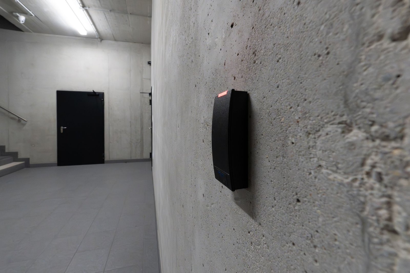 A wall-mounted access card reader beside a corridor door