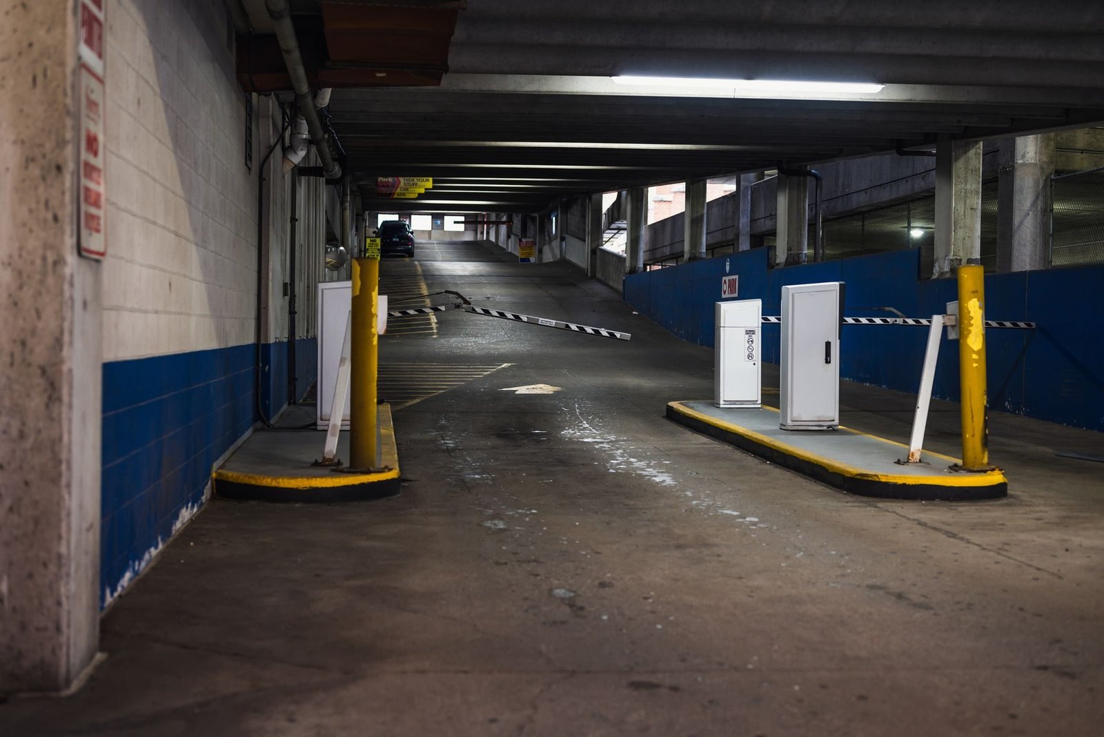 The entrance ramp of a car park with a barrier and ticket posts