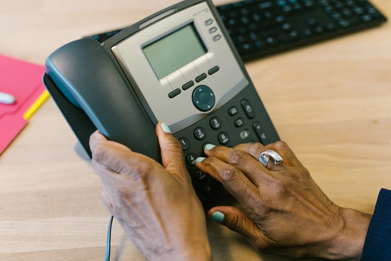 A hand lifting the handset of a desk telephone