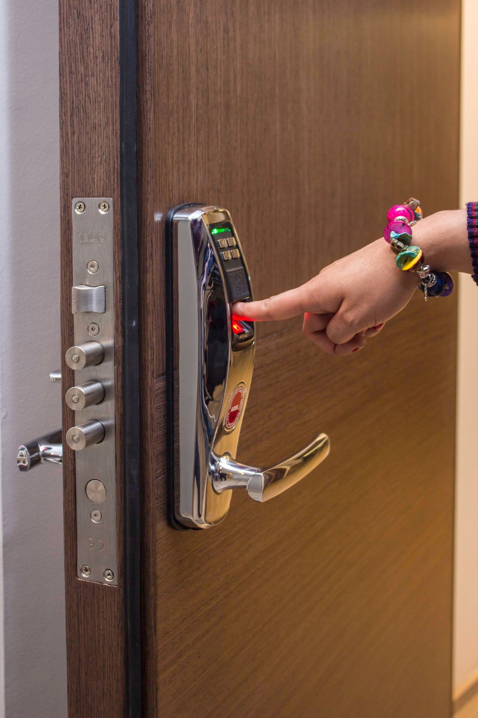 A finger on the reader of a smart door lock