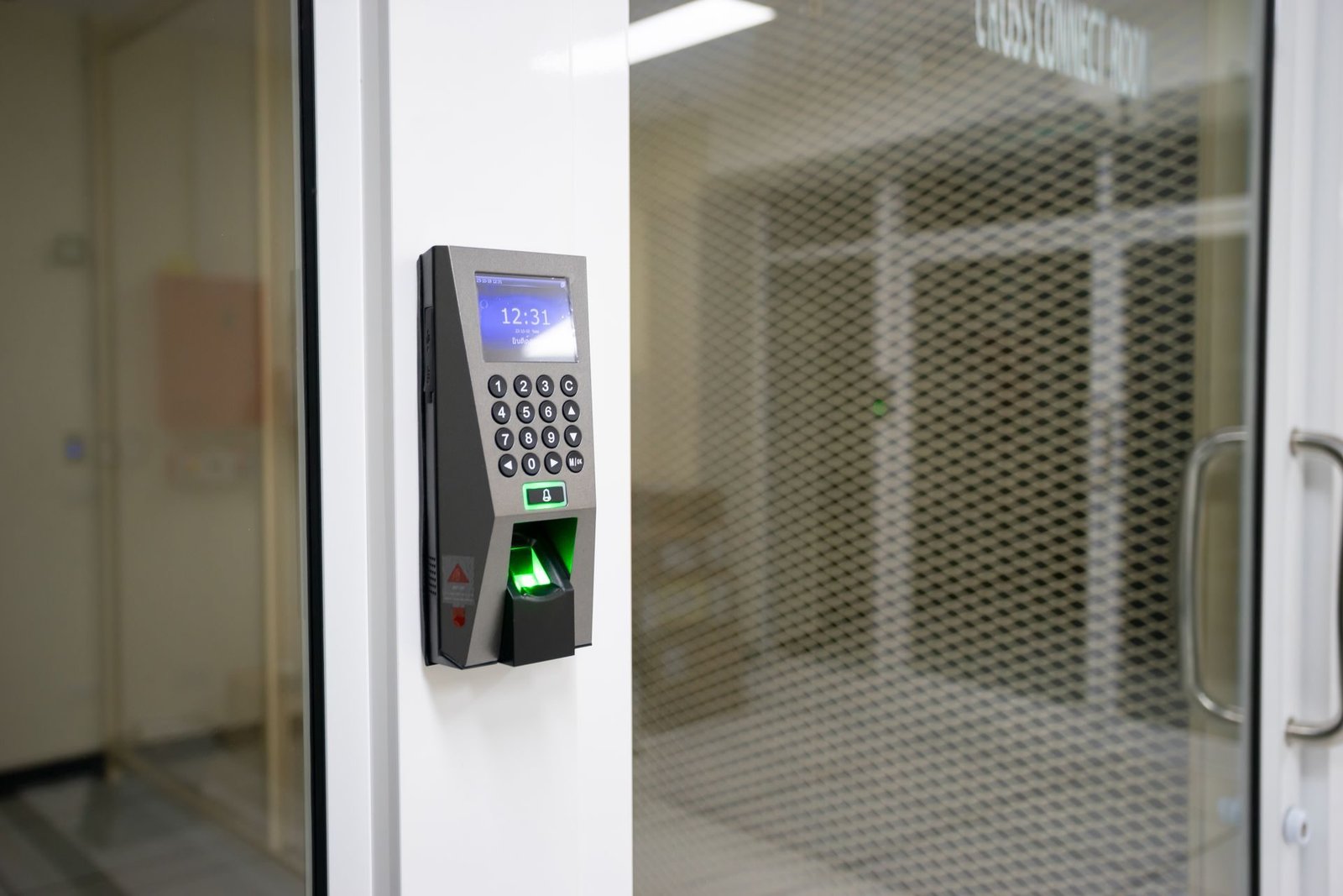 Fingerprint access scanner beside a glass office door