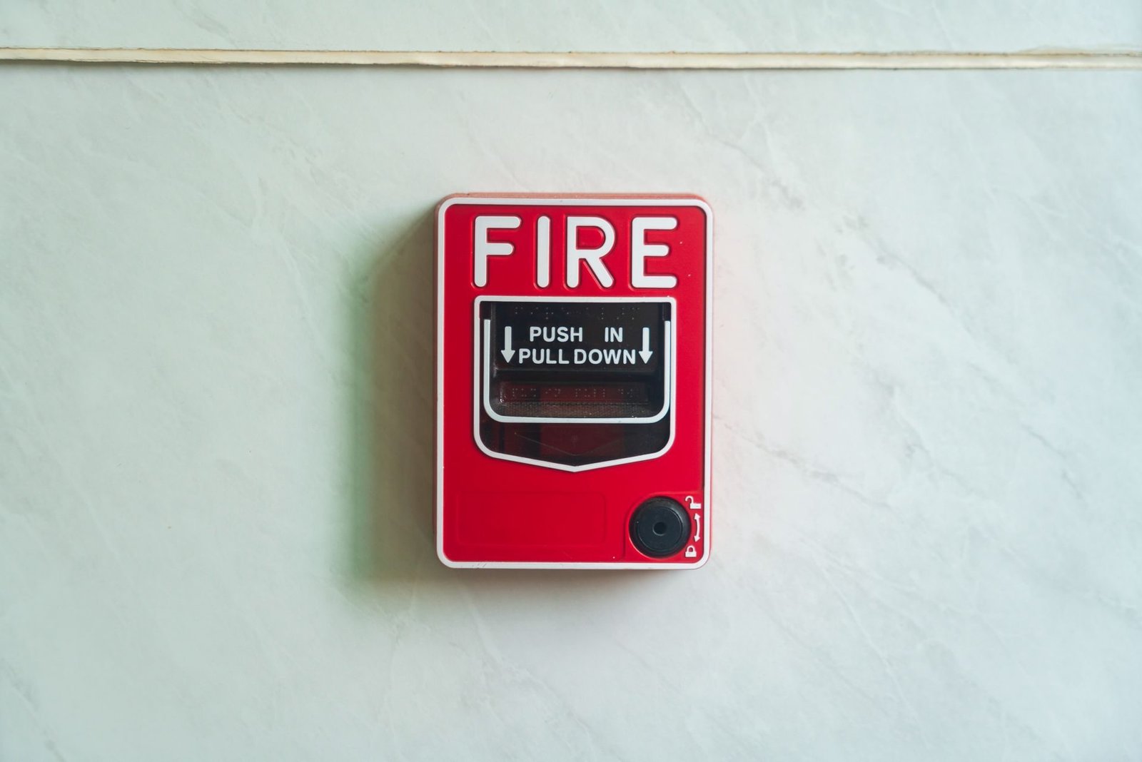 Red fire alarm call point mounted on a wall