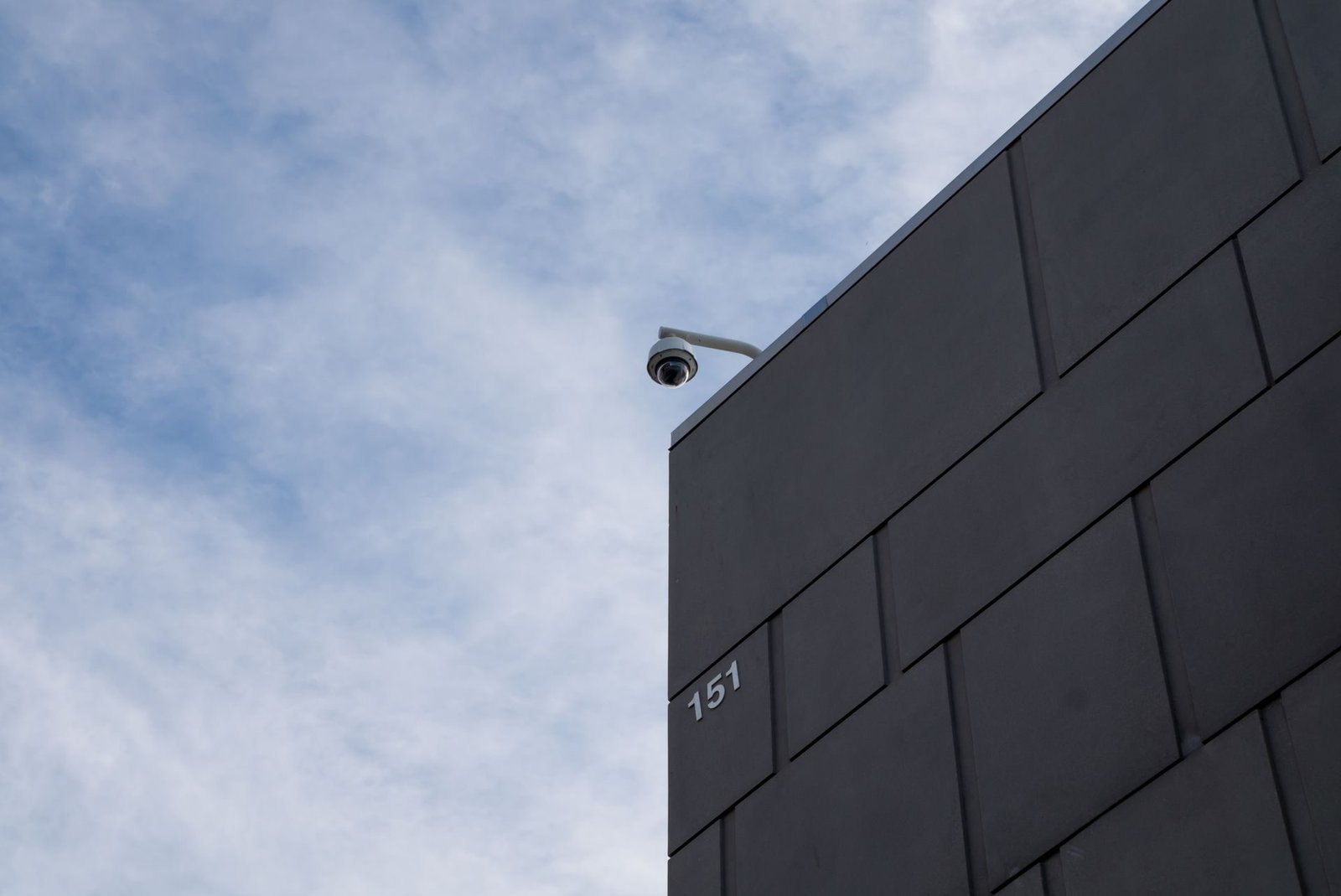 A security camera fixed to the corner of a modern building