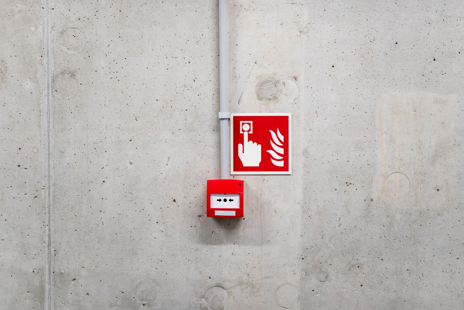 A fire alarm call point and sign on a concrete wall