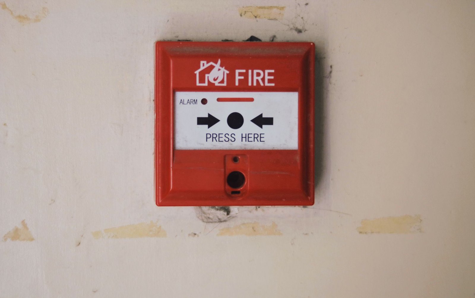 A red manual fire alarm call point on a wall