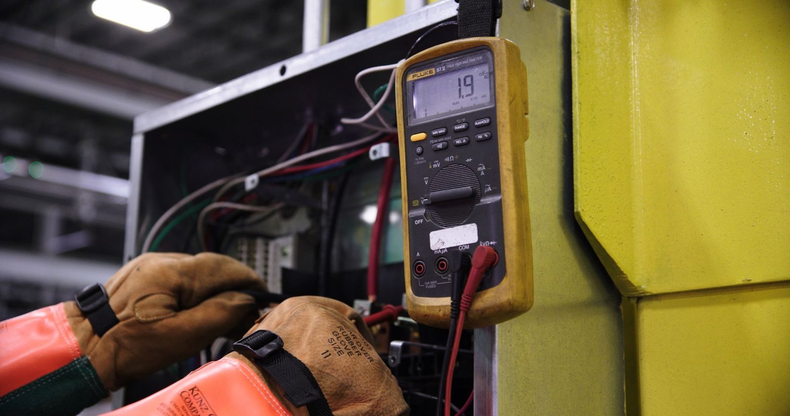 Hands testing an electrical panel with a digital meter