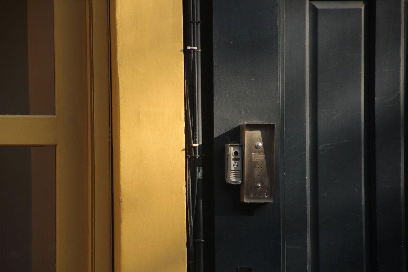 A door phone station mounted beside a black entrance door