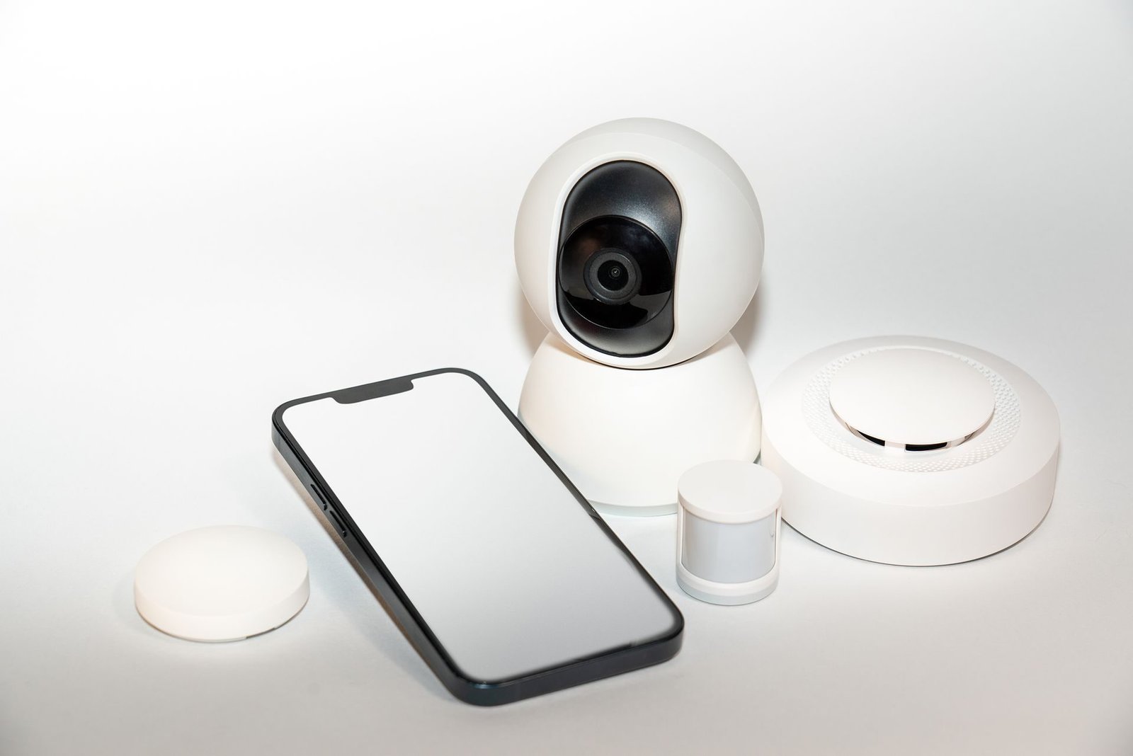 A white Wi-Fi security camera beside a smartphone